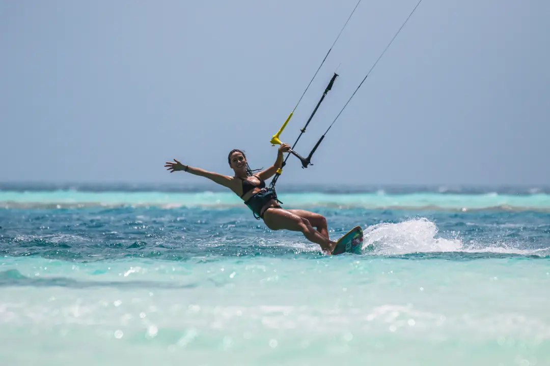 Mulher sorrindo praticando kitesurf em águas calmas